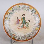 A Japanese Satsuma pottery dish, Meiji Period, decorated with three figures in a garden of