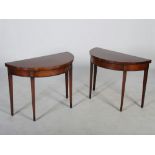 A pair of George III mahogany and boxwood lined demi lune card tables, the hinged tops opening to