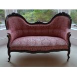 A Victorian rosewood double chair back sofa, the scroll and foliate carved top rail above a button