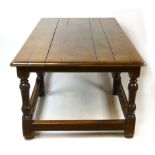 A 17th century style oak refectory table, planked top with moulded rim, raised on block and turned