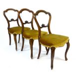 A set of three Victorian walnut balloon backed dining chairs with carved back rest, serpentine