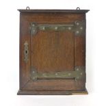 An Arts & Crafts style oak corner cupboard with heart shaped applied hinged decoration and