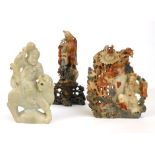 Three Chinese soapstone carvings, the first of a figure standing with a basket on a rocky outcrop,