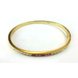 A 9ct gold bangle channel set with twelve diamonds and six rubies. CONDITION REPORT: Weight