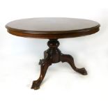 A mahogany circular tilt top dining table, later 19th century, on a turned column and carved