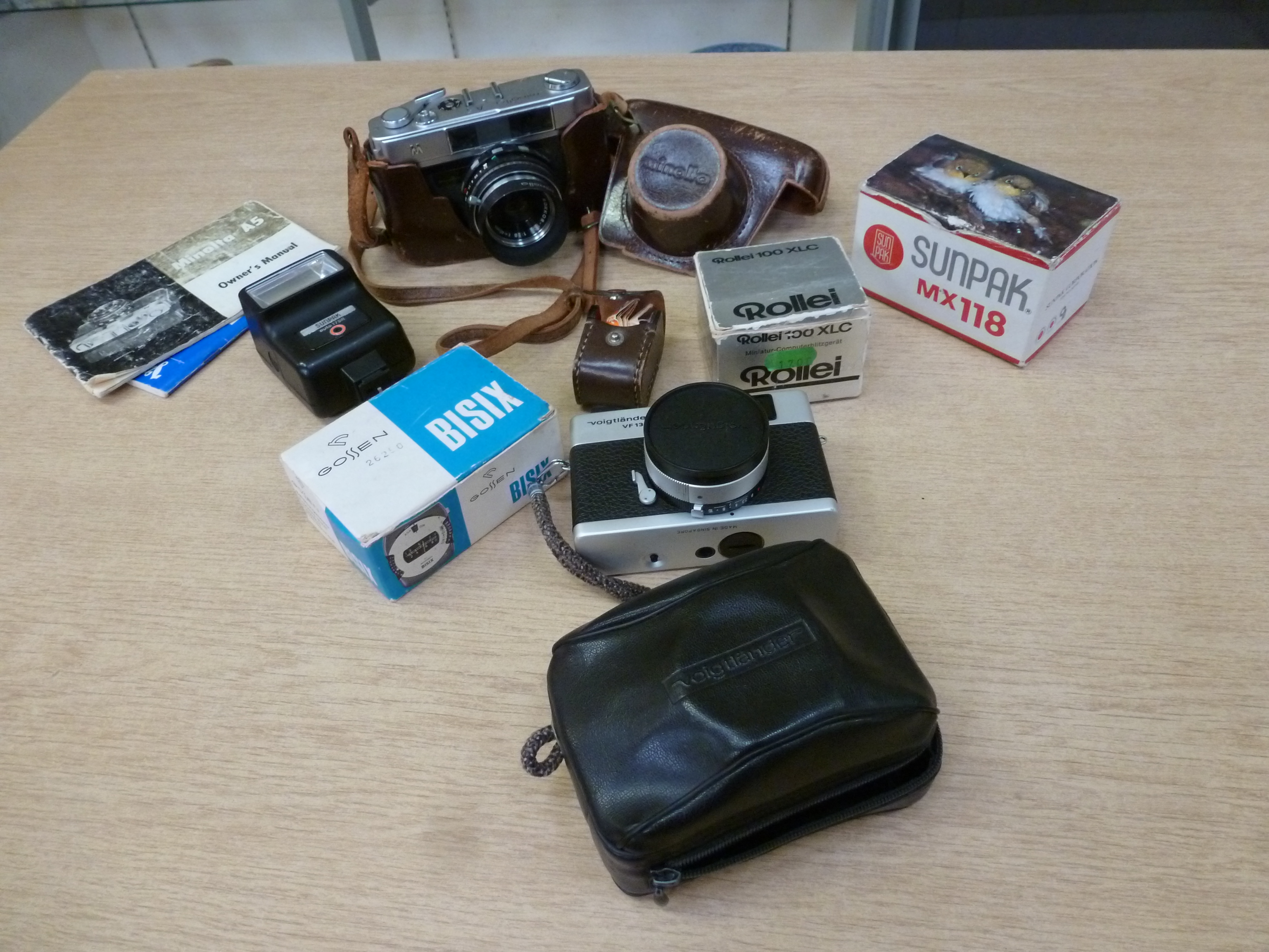A Minolta A5 camera case with Rokkor-TD1 to 28 lens together with a Voigtlander VF135 camera and