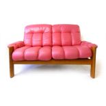 A 1970's teak two-seater sofa of organic form with fuchsia pink leather upholstery, l. 146 cm