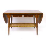 A 1950's walnut drop-end coffee table, the top suspending two drawers over a wickerwork second tier,