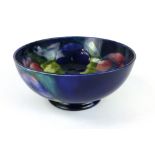 A Moorcroft footed bowl in the Pansy pattern on blue ground, impressed, painted and paper label to