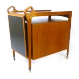 A 1960's teak and laminate trolley of organic form, the sliding top over a suspended two door and