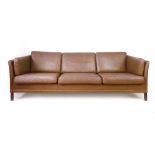 A 1970's brown leather three-seater sofa on mahogany square legs, in the manner of Borge Mogensen,