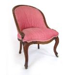 A Victorian walnut framed nursing chair with arched back, serpentine seat and foliate carved