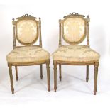 A pair of French gilt wood salon chairs, ribbon carved back rests, with shield shaped cushion