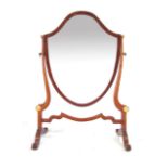 A Hepplewhite style mahogany shield shaped toilet mirror on scrolling supports. h. 52 cm CONDITION