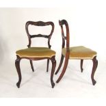 A pair of Victorian rosewood balloon back dining chairs with carved decoration, serpentine seats and