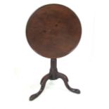 A George lll mahogany circular tilt top occasional table, the tray top on a baluster turned stem and