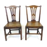 A pair of George lll oak dining chairs in the Chippendale style with pierced splats and solid seats.