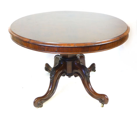 A Victorian rosewood oval tilt top breakfast table, raised on a foliate carved quadripartite