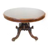 A Victorian rosewood oval tilt top breakfast table, raised on a foliate carved quadripartite