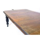 A late Victorian oak wind out dining table of canted rectangular form, with two extra leaves,