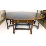 A large oak oval drop leaf dining table, raised on turned supports. l. 168 cm, w. 220 cm