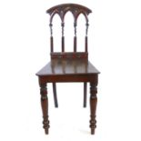 A Victorian mahogany Gothic style hall chair with arched, pierced back rest CONDITION REPORT: Splits