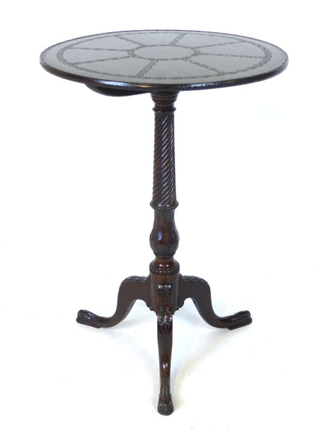 A mahogany circular tilt top occasional table, carved top above a wrythen and foliate carved