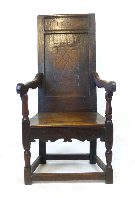 An oak joined elbow chair, possibly late 16th Century, the back carved with the date 1591, flanked