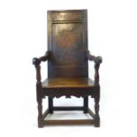 An oak joined elbow chair, possibly late 16th Century, the back carved with the date 1591, flanked