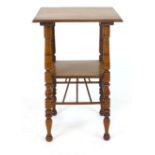 An arts and crafts style walnut two tier occasional table, designed by E W Godwin, with spindle