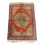 A Persian silk rug, central foliate medallion on a red ground, multi strap border and signature.