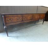 An oak dresser base, two plank top above four cross banded drawers, cabriole legs. l. 250 cm.