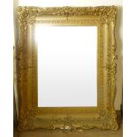 A large gilt framed mirror with scrolling foliate and floral decoration surrounding the