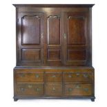 An oak livery cupboard, 18th Century and later, a pair of shaped panel doors flanking a central