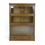 A Globe Wernicke oak three tier bookshelf on a drawer plinth base, applied label to one, h. 125 cm,