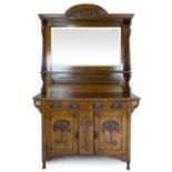 An oak Arts & Crafts style mirror backed sideboard with foliate carving and piercing to the base