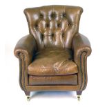 A modern leather armchair with button back scrolling arms and loose cushion on brass casters
