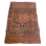 A Persian carpet with a central floral medallion on a blue and red ground with scrolling stylized