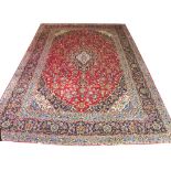 FINE KASHAN CARPET, 420cm x 300cm, of palmettes and vines with sapphire and ivory medallion on ruby