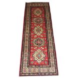 KAZAK RUNNER, 229cm x 81cm, of multiple polychrome medallions on a cerise field within bands and