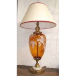 TABLE LAMP, amber glass with gilt detail and a cream shade having a red trim, 83cm H overall.