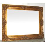 WALL MIRROR, 19th century style gilt framed with rectangular bevelled plate and ornate swept border,