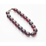 An amber necklace of deep red colour, seventeen large and two small beads, silver clasp Length: