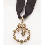 An Edwardian pearl and peridot set pendant of open circular form with bow motif, with millegrain set