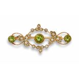 A peridot and pearl set broochof scrolling design, set throughout with small seed pearls and three