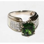 A 14 carat white gold ring set with diamonds with a green tourmaline to the centre