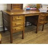 An early 20th century oak library table or desk with shaped top over six small drawers with shaped