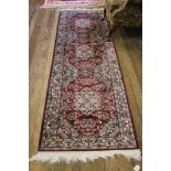 A red ground wool multicolured floor runner, 250cm x 75cm