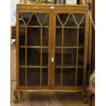 An early 20th century mahogany display cabinet with shaped top, twin astragal doors with shelved