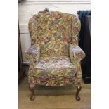 A Victorian-style mahogany framed floral fabric upholstered wingback armchair, raised on cabriole